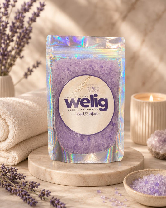 Purple bath salt package with 'welig' branding on a wooden surface with lavender and candles.